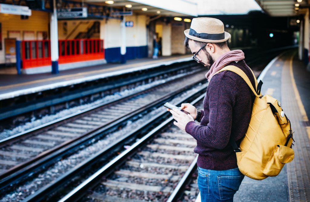 Man waiting for train looking at his smartphone